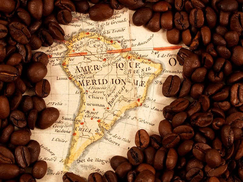 une vieille carte de l'amérique du sud entourée de grains de café torréfiés.