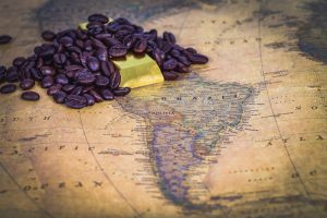 un tas de grains de café et un morceau de chocolat emballé reposent sur une carte antique de l'amérique du sud, avec le brésil bien en évidence.